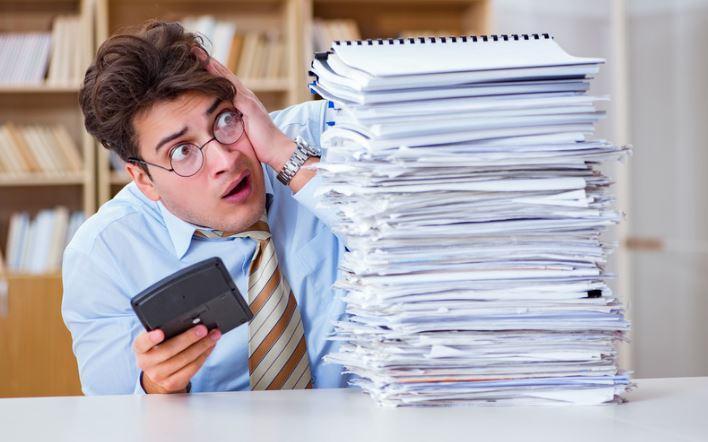 Man kijkt verschrikt naar stapel papieren